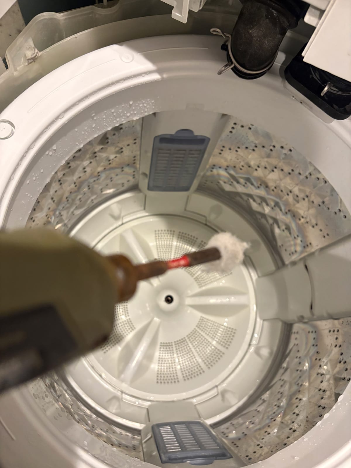 ブラシで洗濯機の槽内部を洗浄する手元