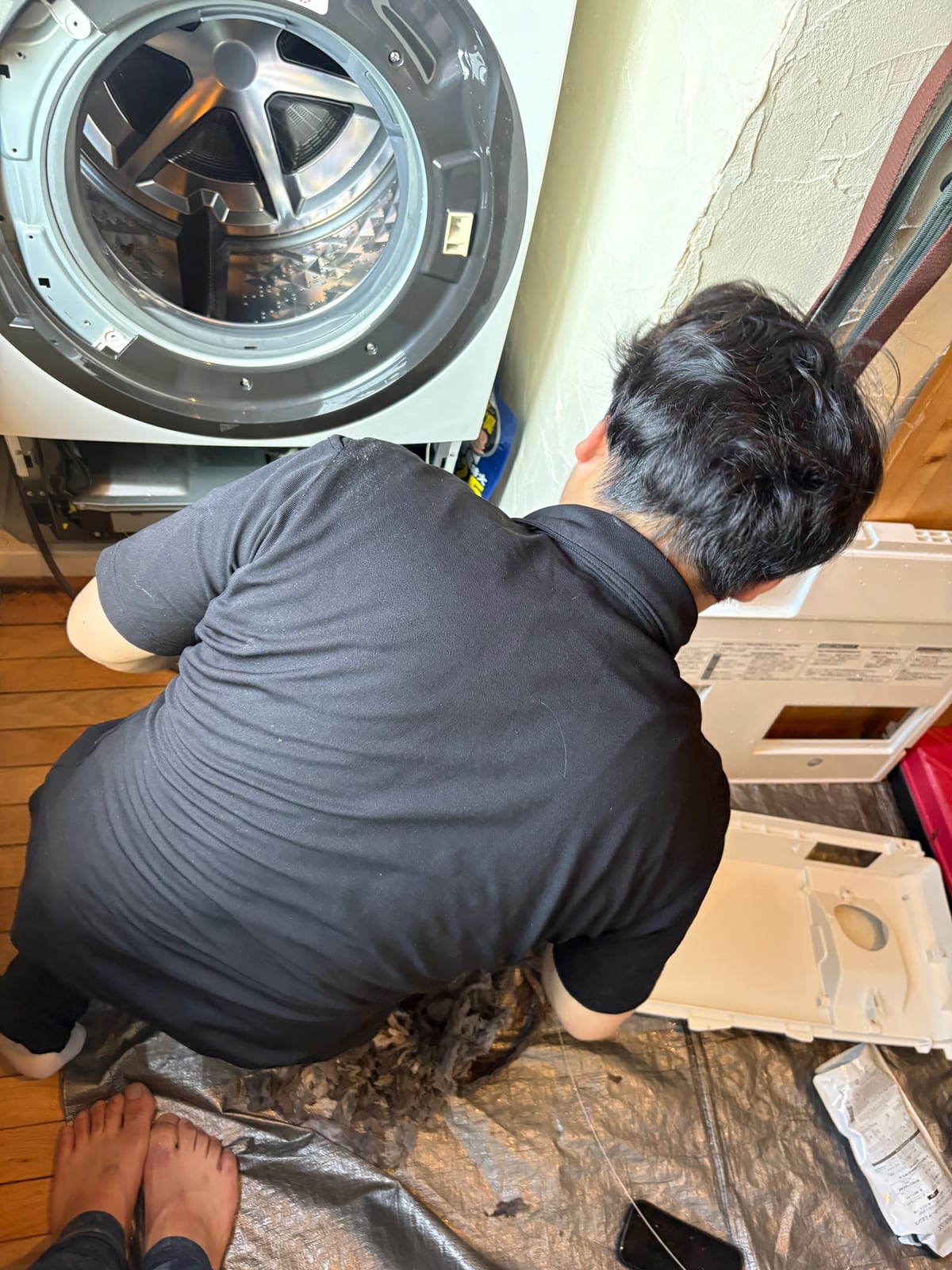 外装を外したドラム式洗濯機の前で作業するスタッフ